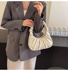 Detail of off-white ruched dumpling bag texture paired with a brown blazer