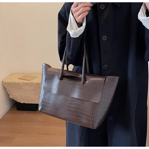 Detail of dark brown faux crocodile embossed tote bag with flap and dual handles