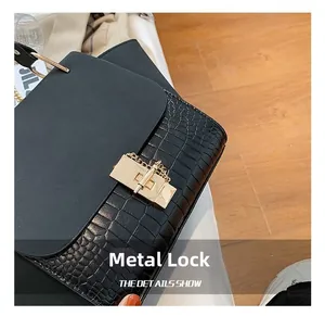 Close-up of golden metal lock and chain on black crocodile texture handbag
