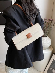Close-up of minimalist beige woven baguette bag with brown leather accents and slim strap