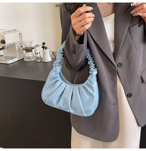 Close-up of light blue pleated underarm bag worn on shoulder for a chic urban style
