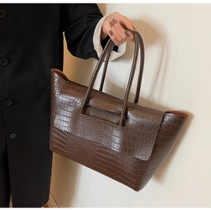 Detail of large brown crocodile pattern tote bag with polished synthetic leather finish