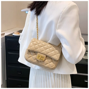 Beige quilted shoulder bag with gold hardware worn over a white blazer suit