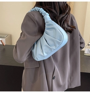 Light blue pleated underarm cloud bag shown from side view on model shoulder
