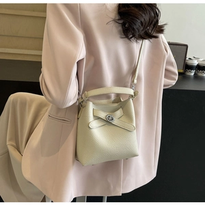 Detailaufnahme einer cremefarbenen Beuteltasche mit Drehverschluss an einem Model