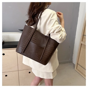 Close-up of deep brown crocodile pattern tote bag showing texture and shoulder strap fit