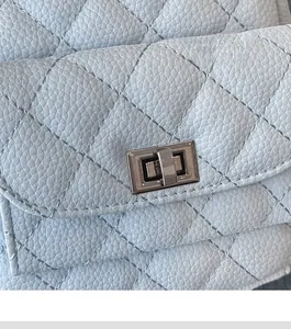 Close-up of light blue quilted leather mini bag with high-quality metal turn-lock closure