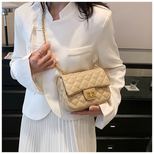 Detail of beige quilted crossbody bag with gold metal lock and leather chain strap