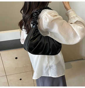 Detail of black pleated cloud bag with scrunchie style strap on a white shirt