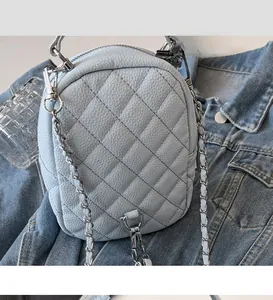 Detail of light blue quilted mini backpack featuring detachable silver chain straps