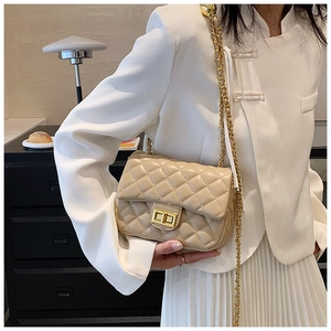 Close-up of beige quilted chain bag with golden metal ball and turn-lock closure