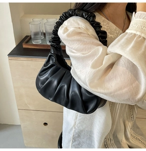 Detail of black pleated cloud bag with soft texture and elegant ruched strap
