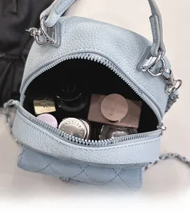 Top view of open blue mini quilted bag showing interior space with cosmetics and silver chain