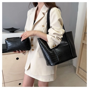 Detail of black crocodile pattern tote bag with matching pouch on beige blazer