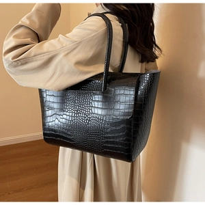 Detail of black faux leather tote bag showing large capacity and crocodile texture
