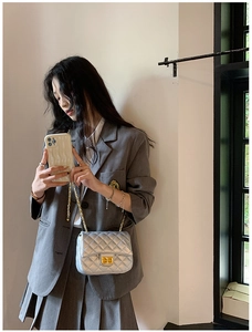 Close-up of silver quilted crossbody bag featuring a golden clasp and chain strap