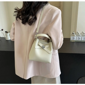 Schicke beige Beuteltasche aus Leder zu einem rosa Anzug in einem Café-Ambiente