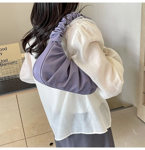 Close-up of purple pleated cloud shoulder bag showing the ruched strap and soft PU texture