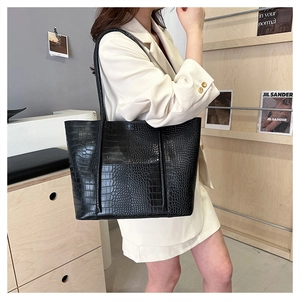 Detail view of black crocodile pattern tote bag featuring premium leather texture and strap