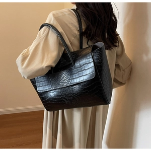 Close-up of black crocodile embossed tote bag with flap and slim shoulder strap