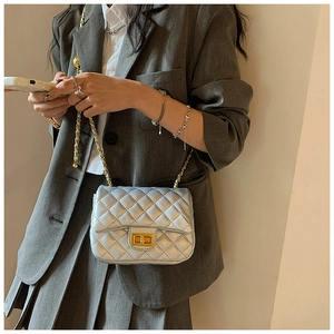 Detail of silver quilted crossbody bag featuring golden chain strap and metal turn-lock