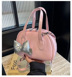 Detailansicht einer rosa Muschel-Handtasche mit stilvollem silbernem Schleifenanhänger