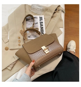 Close-up of khaki wing bag with crocodile pattern leather and gold twist lock detail
