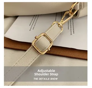 Detail of adjustable shoulder strap with gold metal buckle on cream PU tote bag