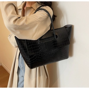 Detail of the black crocodile pattern texture and fold-over flap on the large tote bag