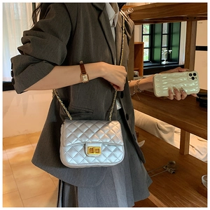 Detail of silver quilted leather bag with gold clasp and chain strap on shoulder