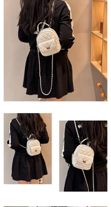 Detail of white quilted mini backpack featuring chain straps and metal turn-lock closure