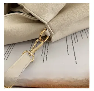 Detailed macro view of the gold-tone lobster clasp and hardware on a beige tote bag
