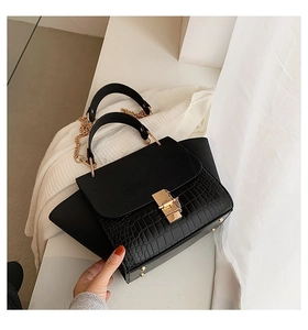 Detail of black crossbody bag featuring crocodile texture and gold metal clasp closure