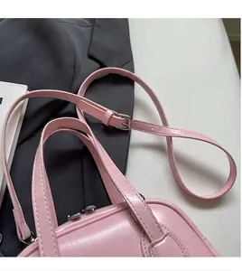 Detailed close-up of pink shell bag with adjustable strap on a grey suit jacket