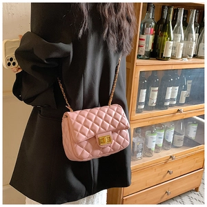 Detail of pink quilted leather chain bag worn on shoulder over a black blazer