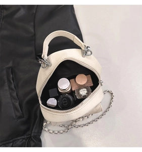 Top view of compact lychee grain leather handbag with chain strap and cosmetic items