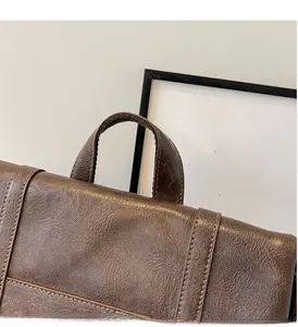 Detail der braunen Vintage-Ledertasche mit robustem Griff und Texturmaserung