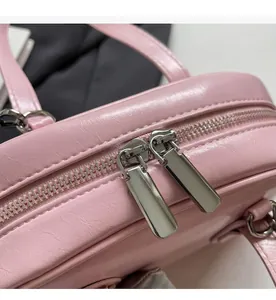 Close-up of dual silver metal zippers on smooth pink textured faux leather shell bag