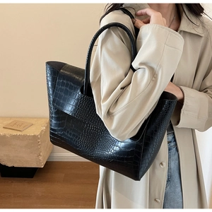 Close-up of black crocodile embossed leather tote bag on model for daily commuting