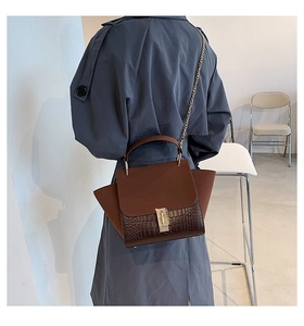 Detail showing brown crocodile textured leather and metal buckle on chain shoulder bag