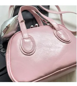 Close-up of pink glossy PU leather shell bag with textured surface and silver heart charm