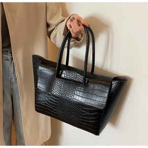 Macro detail of glossy crocodile pattern texture on a black faux leather tote bag