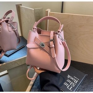Detailansicht der rosa Eimer-Tasche aus Narbenleder mit silbernem Drehverschluss und Riemen