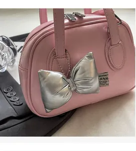 Detailed close-up of a pink shell handbag with a silver butterfly charm and metallic zipper
