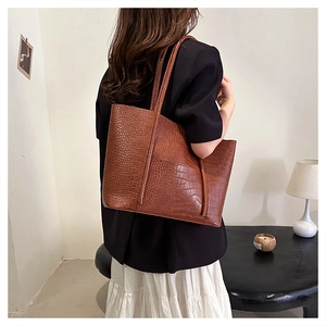 Detail view of a large brown crocodile pattern tote bag shown from a back-wearing perspective