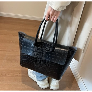 Detailed macro view of the glossy black crocodile embossed texture on a large tote bag