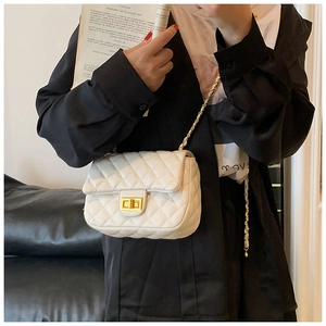 Detail of white quilted crossbody bag with gold chain strap and metal turn-lock closure