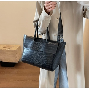 Detail of black faux crocodile skin texture on a stylish large tote bag with top handle