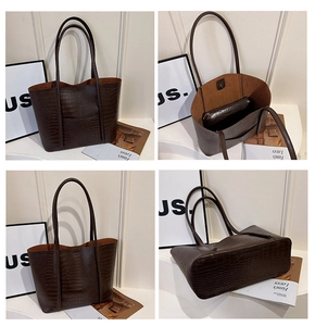 Detail view of large dark brown tote bag with crocodile texture and matching clutch bag