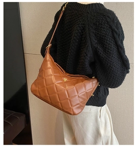 Caramel brown quilted leather shoulder bag featuring a small golden flower-shaped buckle